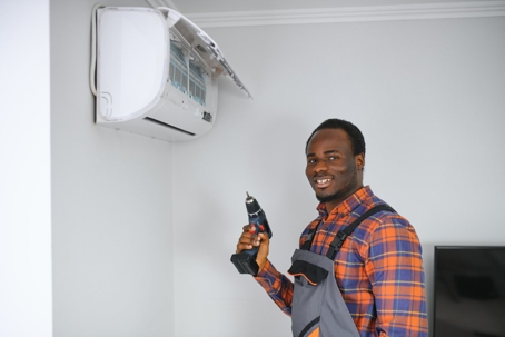 A cheerful technician stands ready to repair a mini-split AC unit.