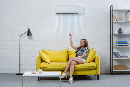 A person sits in a living room under an air conditioner.