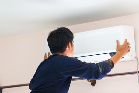 Here's a description of the image: A technician installs a ductless air conditioner.